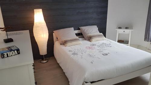 um quarto com uma cama com lençóis brancos e um candeeiro em Villa Helvetia Wifi em Mers-les-Bains