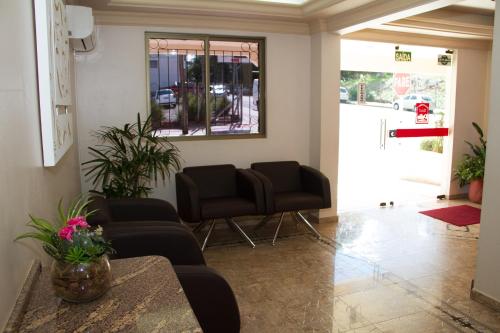 a living room with two chairs and a table at Hotel Pallis in Erechim