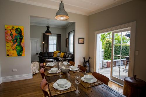 a dining room with a table and chairs and a living room at Coghill Cottage in Whitianga