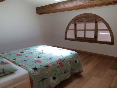 Zimmer mit einem Bett mit einer Decke und einem Fenster in der Unterkunft La Petite Maison Rouge in Mèze