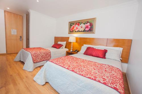 a hotel room with two beds with red pillows at Hotel Casa Mahanaim Colferias, Bogotá in Bogotá