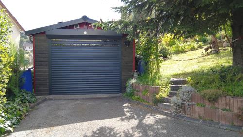 a garage with a blue door in a yard at La Cadanise, Suite Étoilée in Saint-Éloy-les-Mines