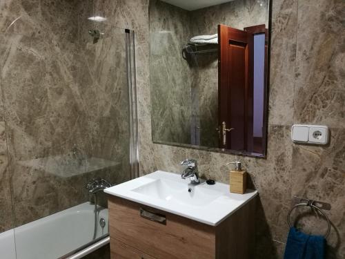 een badkamer met een wastafel, een spiegel en een bad bij Apartamento Aldama en el centro de Sanlúcar de Barrameda in Sanlúcar de Barrameda