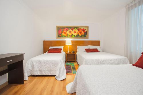 a bedroom with two beds and a table with a lamp at Hotel Casa Mahanaim Colferias, Bogotá in Bogotá