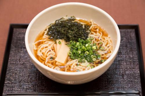 
a bowl filled with noodles and vegetables on a table at Dormy Inn Premium Shibuya-jingumae in Tokyo
