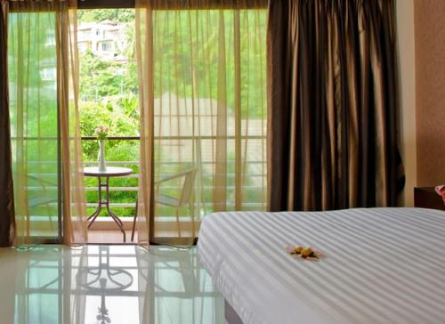 a bedroom with a bed and a view of a balcony at Mellow Space Boutique Rooms in Karon Beach