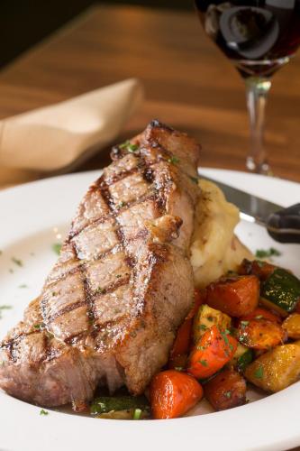 a steak and vegetables on a plate with a glass of wine at Radisson Hotel Portland Airport in Portland