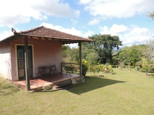 una pequeña casa con un banco en un patio en Pousada Sitio da Serra en Carrancas