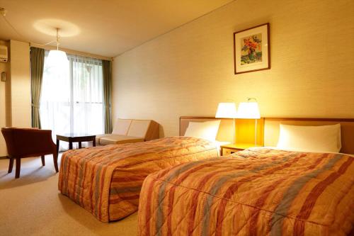 a hotel room with two beds and a chair at Yamanakako-Asahigaoka-Onsen Hotel Seikei in Yamanakako