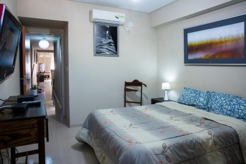 Schlafzimmer mit einem Bett, einem Schreibtisch und einem TV in der Unterkunft Apart Bicentenario in San Miguel de Tucumán