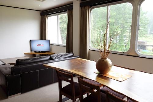 uma sala de estar com uma mesa e um sofá em Ski-in, Ski-out Iwatake Apartments em Hakuba