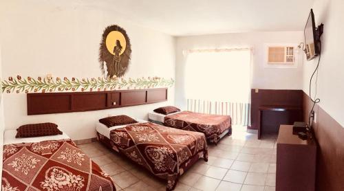 um quarto de hotel com três camas e uma janela em Hotel y R.V. Park El Moro em Loreto