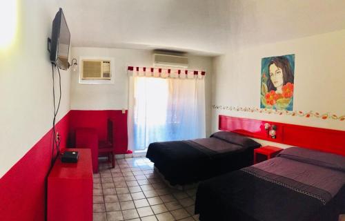 um quarto com 2 camas e uma parede vermelha em Hotel y R.V. Park El Moro em Loreto