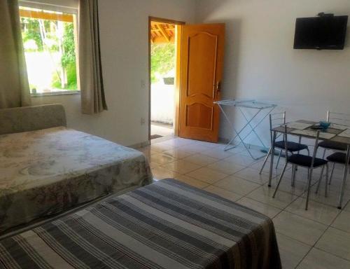 a bedroom with a bed and a table and a door at Chalé Recanto Luz Da Montanha in Águas de Lindóia