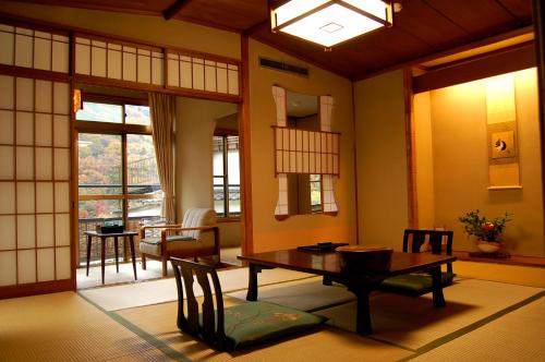 a living room with a table and chairs and a window at Hoeiso in Hakone