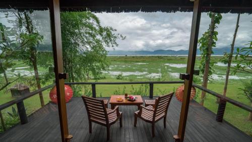 a table and chairs on a deck with a view of a field at Villa Inle Boutique Resort in Nyaung Shwe
