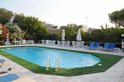 una gran piscina con sillas, mesas y sombrillas en Alkion Hotel, en Stalós