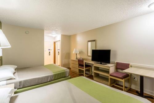 a hotel room with two beds and a desk with a television at Motel 6-Great Falls, MT in Great Falls