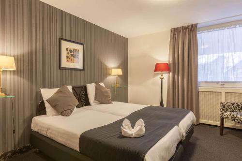 a hotel room with a bed and a window at Amsterdam Hotel Uithoorn in Uithoorn