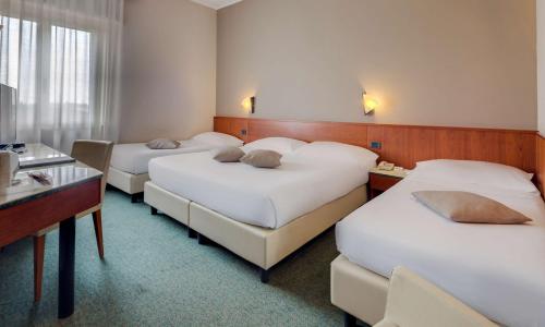 a hotel room with three beds and a desk at Best Western Hotel Turismo in San Martino Buon Albergo