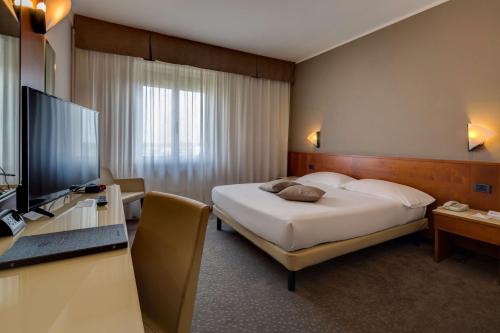 a bedroom with a bed and a desk with a television at Best Western Hotel Turismo in San Martino Buon Albergo