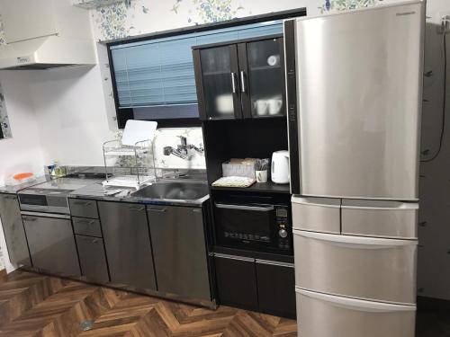 a kitchen with a stainless steel refrigerator and a sink at Hondori Inn in Hiroshima