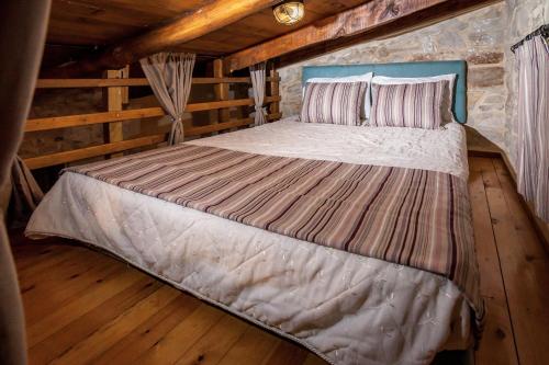 uma cama grande num quarto num chalé de madeira em ARISTIDIS'S PLOUTI MOIRES em Ploutí