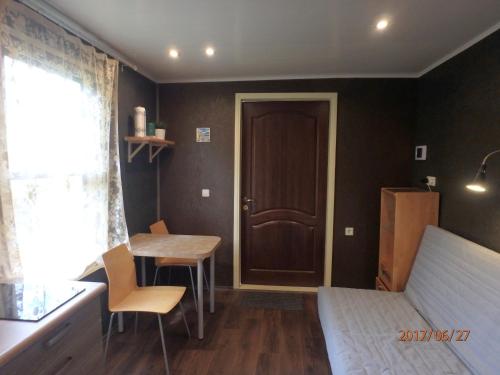 a bedroom with a bed and a table and a door at Melluzi Cottage in Jūrmala