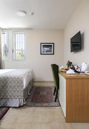 a bedroom with a bed and a desk and a television at The Sephardic House Hotel in The Jewish Quarter in Jerusalem