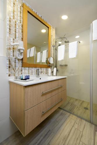 a bathroom with a sink and a mirror and a shower at The Sephardic House Hotel in The Jewish Quarter in Jerusalem