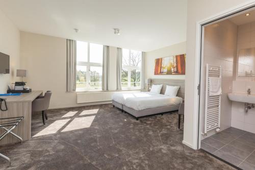 een slaapkamer met een bed, een bureau en een wastafel bij Fletcher Kloosterhotel Willibrordhaeghe in Deurne