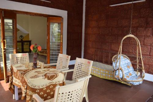 una mesa y sillas en un porche con un columpio en SWAMI home stay panhala, en Panhāla