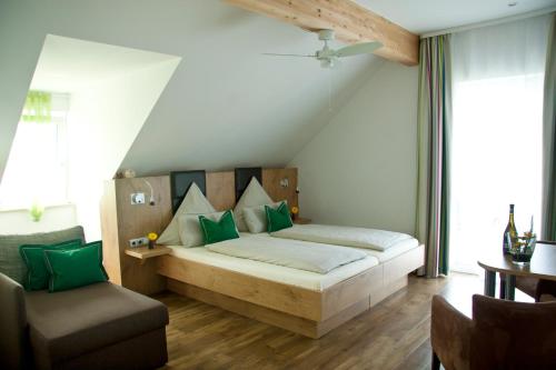 Un dormitorio con una cama con almohadas verdes y una silla en Pension Sperlhof, en Erding