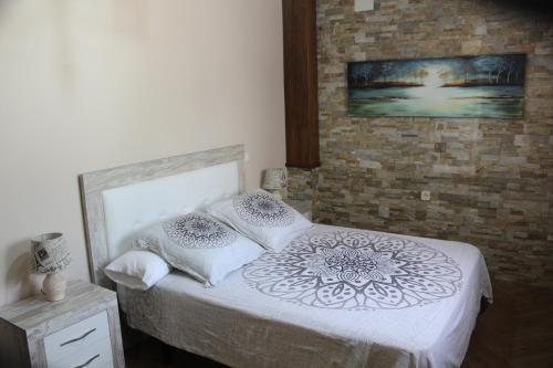 1 dormitorio con 1 cama con sábanas y almohadas blancas en Casa Rural Sierra San Mamede en La Codosera