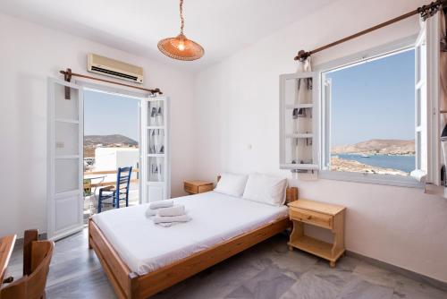 a bedroom with a bed and a large window at Vounali Rooms in Naousa