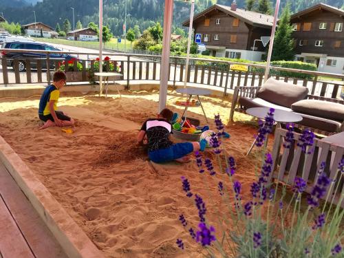 two children playing in the sand in a sandbox at Chalet ELK Lenk in Lenk