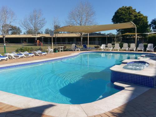 a large swimming pool with chairs and a gazebo at Tuncurry Lakes Resort in Tuncurry