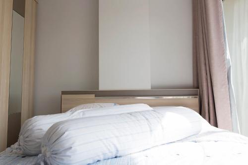 a white bed with a wooden headboard next to a window at Mosaic Condominium A34M by malai in Ban Bua Phut