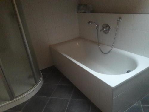 La salle de bains est pourvue d'une baignoire blanche et d'une douche. dans l'établissement Hofschank Reinalterhof, à Malles Venosta