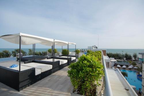 eine Terrasse mit Sonnenschirmen und einen Pool auf einem Gebäude in der Unterkunft Mosaic Condominium A34M by malai in Ban Bua Phut