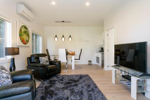 a living room with a couch and a large television at The Retreat Luxury Garden Villa in Taupo