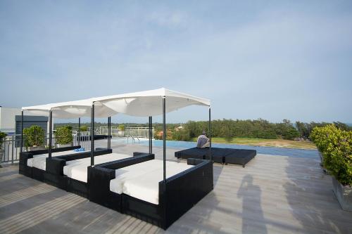 a man sitting on a patio with two beds and an umbrella at Mosaic Condominium by Malai in Mae Pim