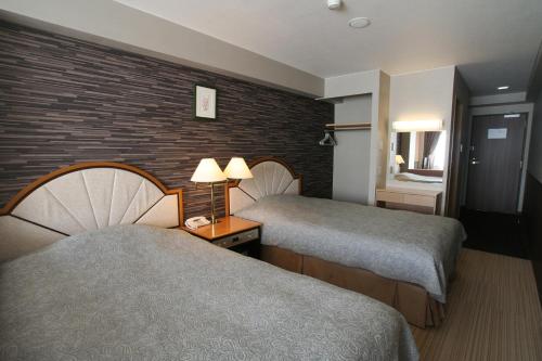 富士河口湖町にある富ノ湖ホテルのレンガの壁のホテルルームで、ベッド2台が備わります。