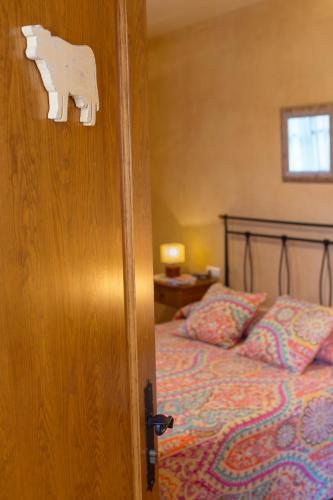 a wooden door with a cow cut out of it next to a bed at Turisme Rural Ca l,Anguila in Peratallada