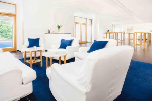 uma sala de estar com mobiliário branco e almofadas azuis em Hotel J, Stockholm, a Member of Design Hotels em Nacka