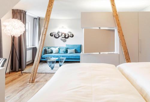 a bedroom with a blue couch in a room at Boutique Hotel Friesinger in Kressbronn am Bodensee