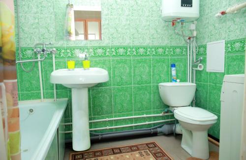 クラスノダールにあるApartments on Zipovskayaの緑のタイル張りのバスルーム(洗面台、トイレ付)