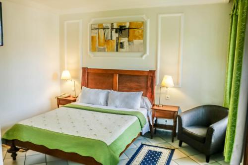 a bedroom with a bed and a chair at Tchero Hotel in Douala