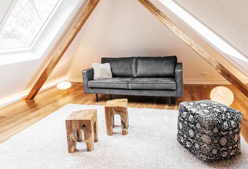 a living room with a black couch and stool at Boutique Hotel Friesinger in Kressbronn am Bodensee