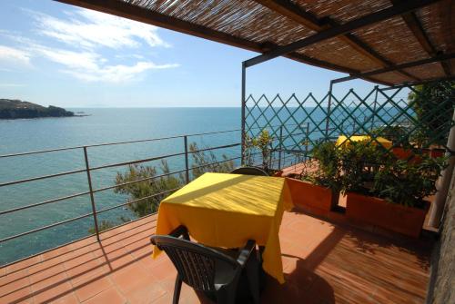 a yellow table and chairs on a balcony overlooking the water at Hotel Baia Del Sorriso in Castiglioncello